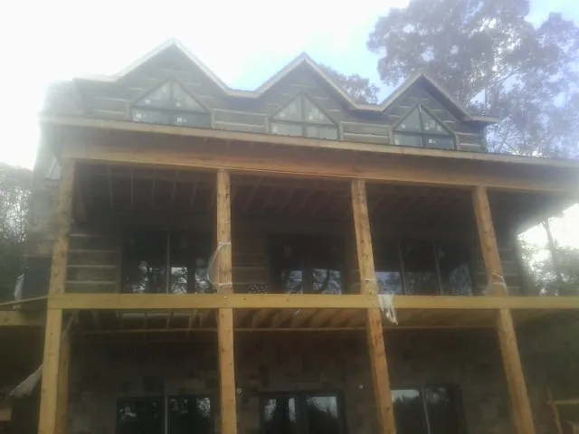 Dormers and porch framing on a large log home under construction — Roof Coating work by our crew in Westmoreland